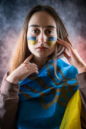 all the emotions of pain, sadness and fear on the face of a young Ukrainian woman with a flag and hope for peace. war of Russiaの写真素材
