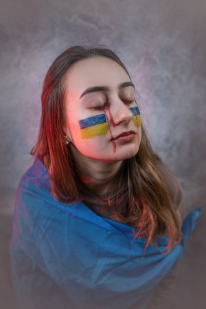 Freedom for Ukraine people, Ukrainian patriot with a flag demonstrates sadness and hope for peaceの写真素材