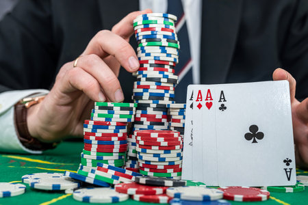 Stylish man in black suit holding play cards and poker chips in casino. Gambling playing concept