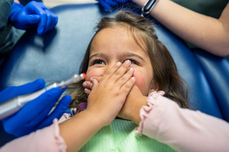 on the dental chair lies a little girl who is about to open her mouth to the dentist. The concept of dental treatment in childrenの写真素材