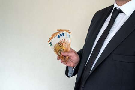 Business man in suit counts euro banknotes at work. concept of wages in productionの写真素材