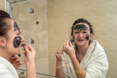 Cute girl treats her acne on the face with a special mask that treats them and promotes healing. Therapeutic mask conceptの写真素材