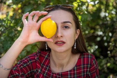pretty woman in chic red checkered dress posing in nature, summer sunny dayの写真素材