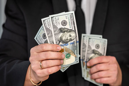 an outstanding man with beautiful strong hands has to hand over a large sum of dollars to the workers. Big and small business conceptの写真素材