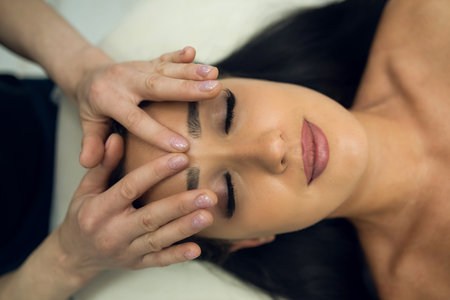Young woman in beauty spa salon having curative facial massage. Relaxing facial massageの写真素材