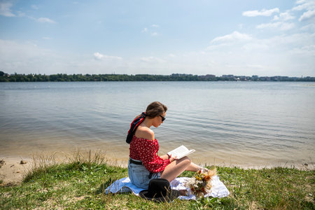 Beautiful woman read book sitting on grass near the lake. lifestyle conceptの写真素材