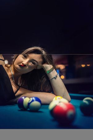 Beautiful lady lying on green snooker table among the balls. lifestyleの写真素材