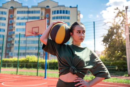 Young pretty sporty caucasian woman hold basketball on basketball court at outdoor, active weekendの写真素材