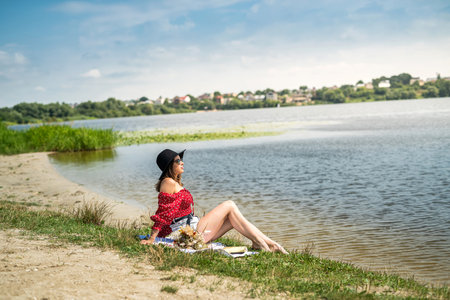 Beautiful woman sit to relax near pond in park. Enjoying nature outdoors. summer dayの写真素材