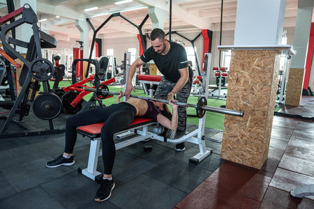 Male instructor exercising with his female client at gym. woman working about the optimal training...