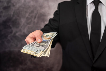 a man with a strong physique in a shirt and jacket holds his own earned dollar bills. The concept of...