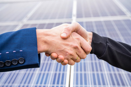 Workers in helmets and work clothes greet each other by the hand before starting work on solar...