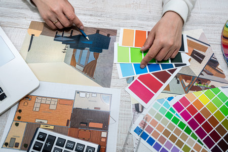 male architect designer in the office selects a palette of colors for drawings of the house on the...