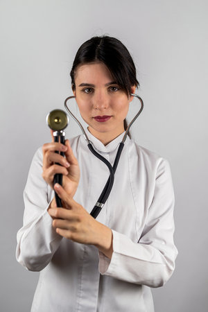 A cheerful nurse is signing documents on a clipboard while looking at the camera. Paramedic in uniform smiling writing on paper and files for notebook. Woman with stethoscope and textbookの写真素材