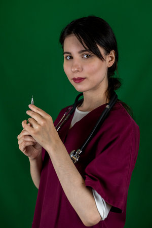 A young female nurse holds a syringe with a needle in her hand in medical clothes isolated. A nurse with a syringe in her hand. A biochemist with a syringe in his hands. biochemist takes blood sampleの写真素材