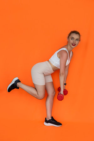 the athletic beauty with a pumped-up body demonstrates which dumbbells she prefers during training....