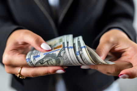 view of female hands in jacket showing pile of dollar banknotes and celebrating isolated on plain background. money in hand. business woman. lady bossの写真素材