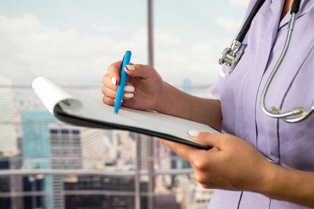 Female doctor person wearing uniform and stethoscope reading patient information document for surgery consultation. a female professional nurse works as a medical consultant in a hospital. healthの写真素材