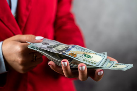 beautiful tender hands of a woman in a jacket hold a stack of US dollars. a woman at a shop. hands...