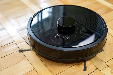 Top view of robot vacuum cleaner on wooden floor with cool remote control. intelligent automated wireless cleaning technology in the living room. close up with copy spaceの写真素材