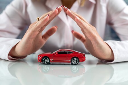 beautiful small car in the hands of a woman at the table. Concept of safe driving. protection of life behind the wheel.の写真素材