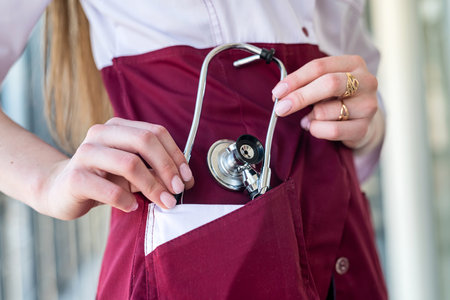A young intern in a gown with a stethoscope poses for the camera in the hospital. woman portrait concept. Medicineの写真素材