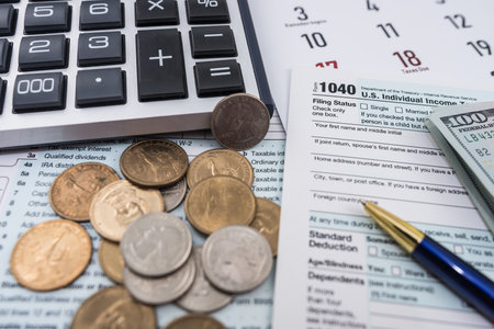 Blank personal income tax return with dollar bills and calculator and pen on calendar page marked April fifteenth. Tax period concept. Internal Revenue Service. tax formsの写真素材