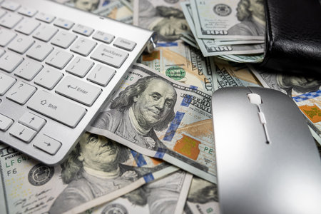 beautiful white computer keyboard on which a large sum of dollars is laid out close by limply...