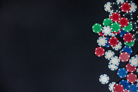 colored casino poker chips scattered on a black table. isolated poker. casino. gambling or games for moneyの写真素材