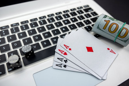 dollar bills and casino dice and cards on laptop keyboard isolated on black background. Gambling. card game conceptの写真素材