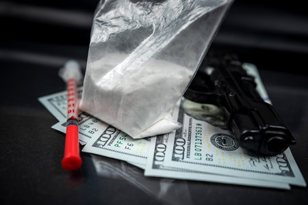 Packages of powdered substances and dollar bills next to a gun and a medical syringe. drug trafficking concept. violation of the law. distribution of drugsの写真素材