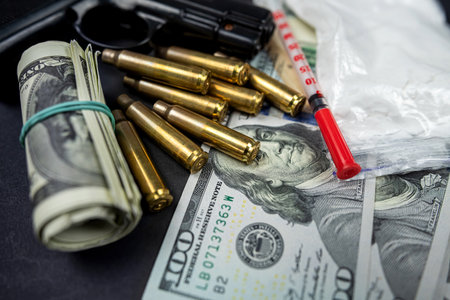 gun with bullets and a syringe and drugs in the form of powder lie on a black table. Dangerous bad habits. drug addiction. drug crime. Sale, storage and distribution of drugsの写真素材