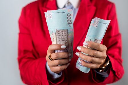 Close up of hands of young rich woman smiling and holding lots of dollar money isolated on plain background. dollars in hand rich womanの写真素材
