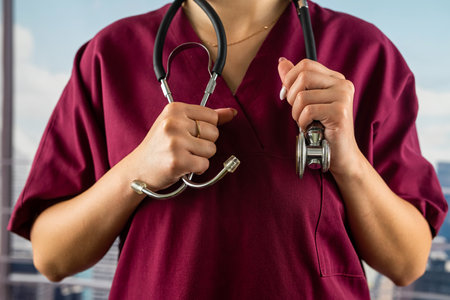 young woman doctor with a stethoscope in her hands in medical clothes is standing in a prestigious hospital. doctor's hands close up. stethoscopeの写真素材
