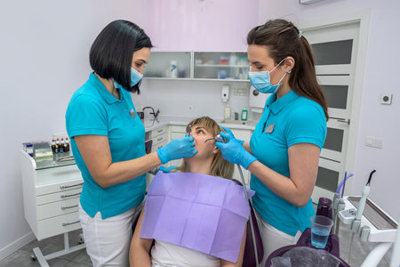 Dentist woman talking to her patient about the treatment of her teeth. The concept of dialogue between dentist and patientの写真素材