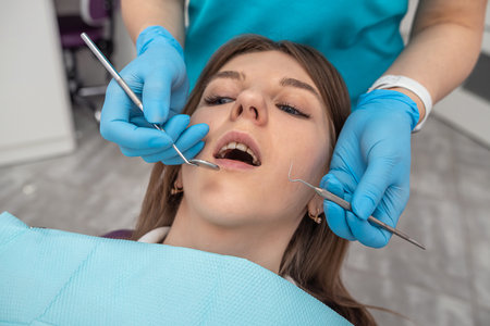 professional woman dentist performs a professional examination of the oral cavity in a beautiful...
