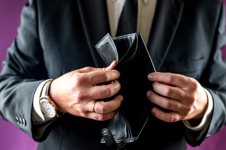 Close-up of a shocked man's hand holding an empty wallet without banknotes. the man is bankrupt. problems with financesの写真素材