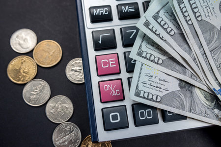 new calculator and dollar bills with coins isolated on black background. dollar exchange rate. crisis. financingの写真素材