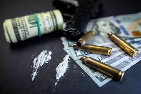 Cocaine in bags next to dollars and a gun isolated on a black background. the concept of breaking the law. storage and distribution of cocaineの写真素材