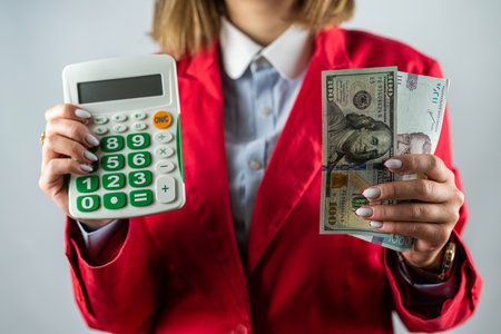 Picture of excited young cheerful woman standing over pink background wearing strapless dress holding money. Looking camera pointing.の写真素材