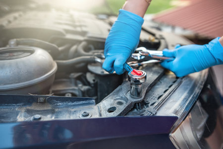 Close-up of auto mechanic's hands using wrench to repair car engine in auto garage. Car care fixed repair and service concepts.の写真素材