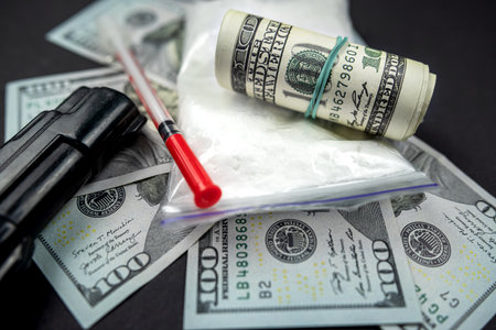 Packages of powdered substances and dollar bills next to a gun and a medical syringe. drug trafficking concept. violation of the law. distribution of drugsの写真素材