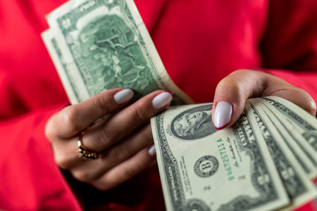 Portrait of cheerful young woman holding money dollar bills in office isolated on plain background. business lady. money. cash dollarsの写真素材