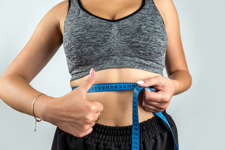 Attractive female body in trendy sportswear with ribbon on plain background. The concept of a healthy lifestyle. diet.の写真素材