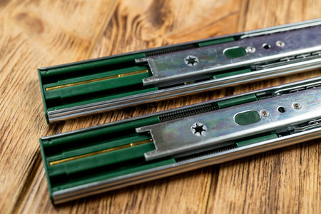 Drawer guides with a steel telescopic rod are placed on the table. Details for kitchen furniture.