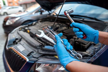 car mechanic or repairman repairs a car engine by hand in a car workshop with a wrench. car service and maintenance. repair services.の写真素材
