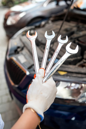 Auto mechanic works and repairs car engine in mechanics garage. car service. Man with wrench in workshop.の写真素材
