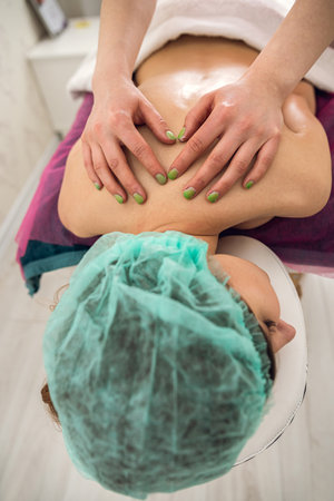 Female client lying on table having rejuvenation massage on back in spa salon. Healthy relaxation lifestyleの写真素材