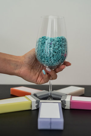 Warm wax in colored cartridges for depilation and granulated wax in a glass stand on a black table....