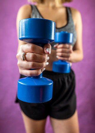 Young fun strong sport sports fitness trainer instructor woman in tracksuit holding dumbbells isolated on plain background. Sport workout conceptの写真素材
